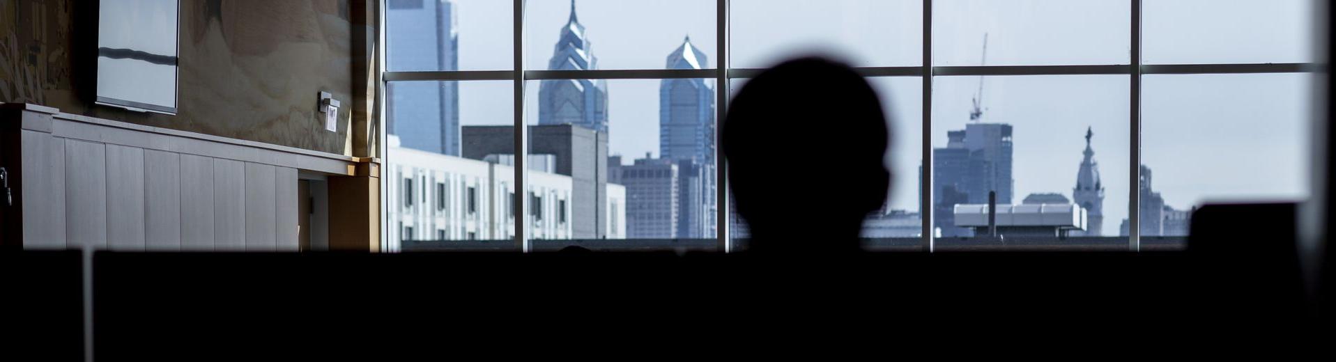 A student looks at the Philadelphia skyline through the windows of a building at PG电子试玩平台.