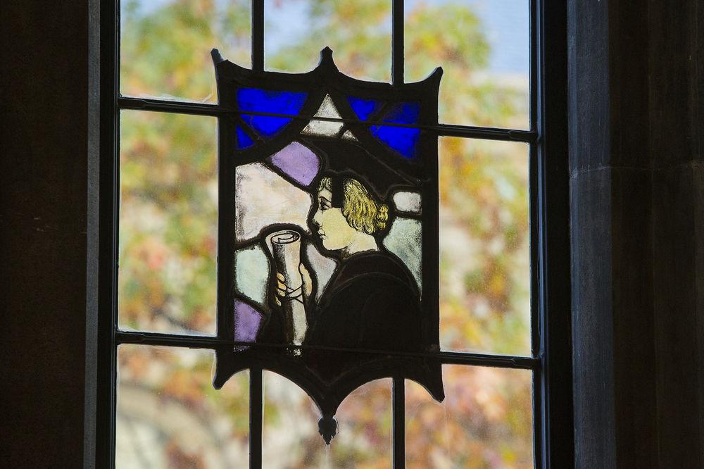 A stained-glass window featuring a graduate holding a diploma.